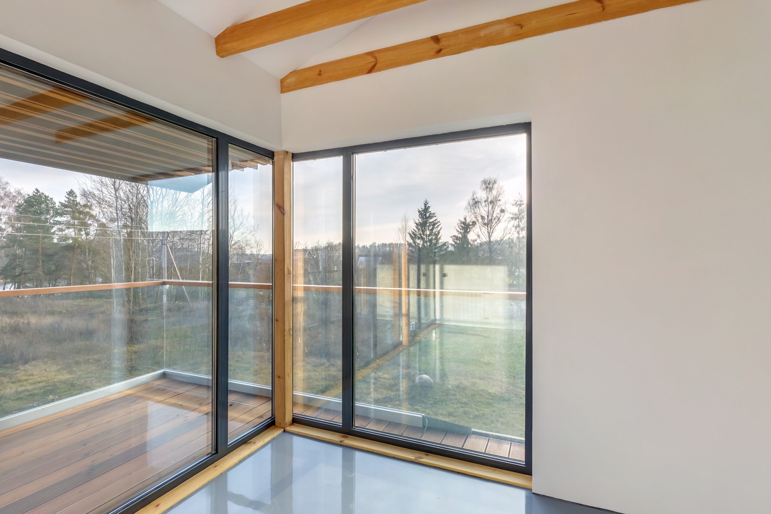 Grote schuiframen in een moderne woning die illustreren hoe groot ramen moeten zijn voor voldoende licht en comfort