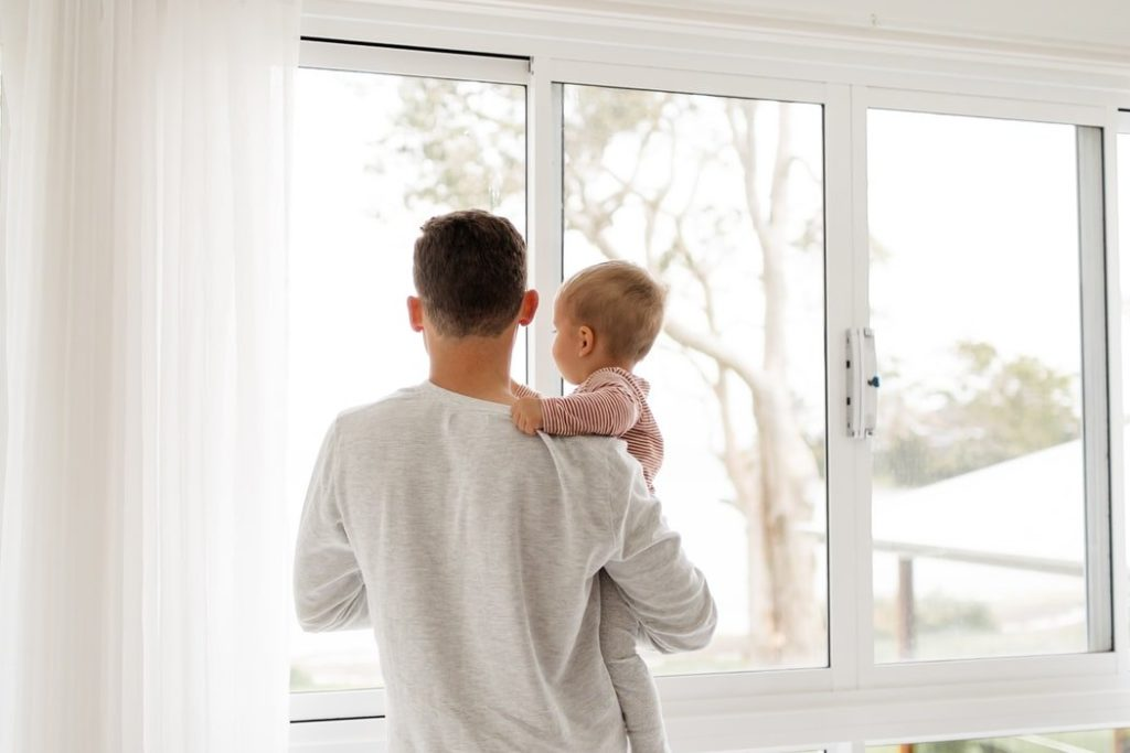 Man met baby bij wit PVC schuifraam