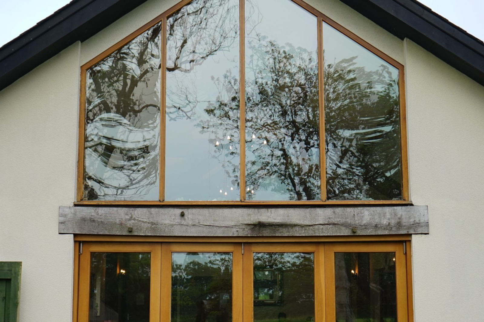 Woning met grote houten ramen en driehoekig glasvlak in gevel
