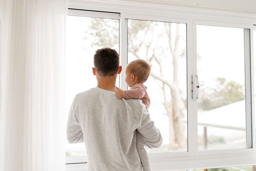 Vader met kind bij nieuw geplaatst raam in lichte woonkamer met veel daglicht